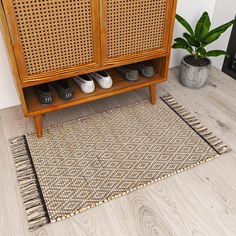 a wooden cabinet sitting on top of a hard wood floor next to a potted plant