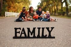 a family sitting on the ground with their name spelled out in front of them,