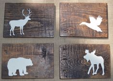 four wooden coasters with white moose and deer silhouettes on them, sitting on a table