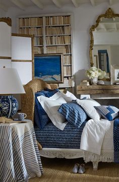 a bedroom with blue and white bedding in front of a book shelf filled with books