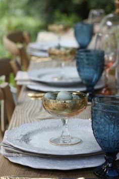 the table is set with blue glassware and place settings for two people to sit at