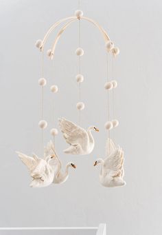 three white doves hanging from strings with balls in the shape of an ornament