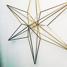 a gold and black metal star ornament on a white wall