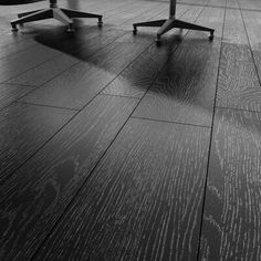 black and white photograph of three chairs in an empty room with wood flooring on the ground