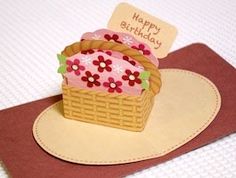 a birthday card with a cupcake in a basket on top of a brown mat