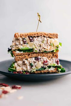 two sandwiches stacked on top of each other with fruit and cheese in the middle, sitting on a black plate