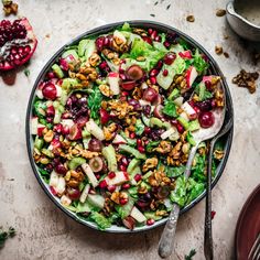 a salad with apples, walnuts and cranberries in a bowl on a table