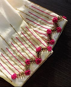 a close up of a piece of cloth on a wooden table with beads and flowers