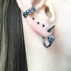 the ear is adorned with three skulls and two piercings that are attached to each other