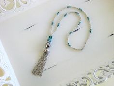 Tassel Necklace handmade by Ralston Originals. This blue tassel necklace is made with a very unique blue bead, with crystals, and silver accents. The necklace is also made with a large sparkling blue crystal bead, and a large silver metal bead. The tassel is made with silver metal Bohemian Silver Tassel Necklace Gift, Silver Bohemian Tassel Necklace As Gift, Silver Bohemian Lariat Tassel Necklace, Adjustable Silver Bohemian Tassel Necklace, Bohemian Silver Adjustable Tassel Necklace, Bohemian Adjustable Silver Tassel Necklace, Silver Bohemian Dangle Tassel Necklace, Handmade Silver Long Tassel Necklace, Silver Tassel Necklace For Festival