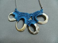 a blue knitted necklace with two horns attached to it