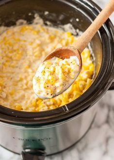 a wooden spoon in a crock pot filled with macaroni and cheese,