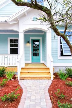 a blue and white house with steps leading up to the front door that leads into the yard