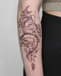 a woman's arm with a tattoo on it that has an image of a dragon and flowers