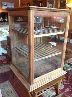 an old wooden display case with glass doors on the front and bottom shelves, in a living room