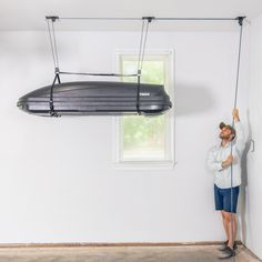 a man is standing in front of a black object suspended from the ceiling by wires