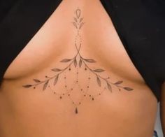 a woman's lower back tattoo with leaves and beads on her ribs, showing the side