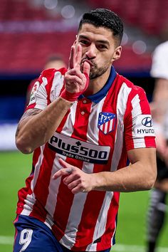 a soccer player is making the peace sign with his hand while standing on the field