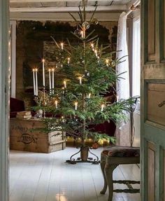 a small christmas tree in the middle of a room with candles on it and a bench