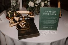 an old fashioned phone sitting on top of a table next to a sign that says our audio voice book