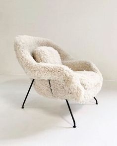 a white chair with black legs and a sheepskin seat cover on it's back