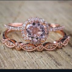 two rose gold wedding rings with an oval cut diamond in the center, on top of a wooden surface