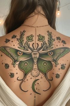 the back of a woman's neck with a green moth tattoo on her shoulder