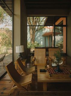 a living room filled with furniture next to a large glass window covered in plants and trees