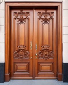 two wooden doors with decorative carvings on the front and side of each door are shown