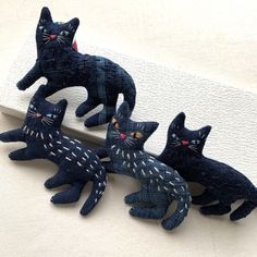 three black cats sitting on top of a white surface next to each other and one cat has red eyes