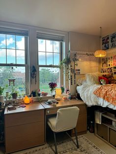 a bed room with a neatly made bed next to two large windows and a desk