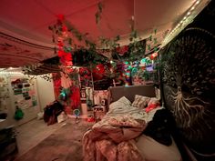 a messy bedroom with lots of clutter on the floor and decorations hanging from the ceiling