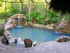 a small pool with a waterfall in the middle and chairs around it, surrounded by palm trees