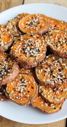 a white plate topped with sliced up sweet potatoes covered in sesame seeds and seasoning