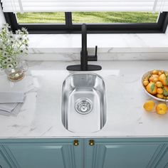 a kitchen sink sitting under a window next to a bowl of fruit