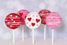 cake pops with hearts on them sitting in front of a white background and silver boke