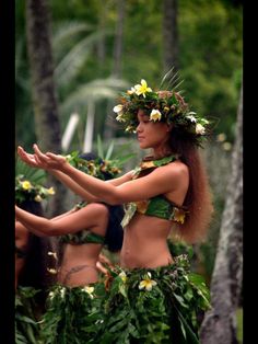 two women dressed in hula skirts and flowers on their heads are standing next to each other