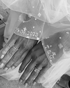 two hands with wedding rings on their fingers, one wearing a veil and the other holding an engagement ring