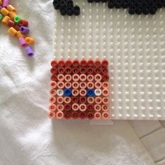 a piece of art made out of legos on a white cloth with beads and bead sprinkles