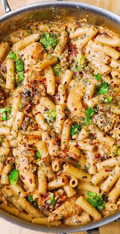 a pan filled with pasta and broccoli on top of a wooden table