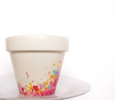 a white cup with colorful sprinkles on it sitting on a saucer