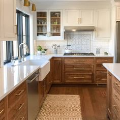 a kitchen with wooden cabinets and white counter tops, along with an area rug on the floor