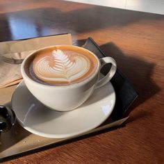 a cappuccino on a saucer with a spoon and fork next to it