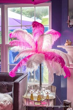 a pink feather centerpiece in front of a window with purple walls and white trim