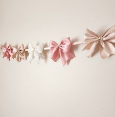 three pink and white bows are hanging on the wall