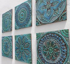 four blue and green tiles are hanging on the wall next to each other in different patterns