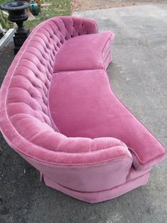 a pink couch sitting on top of a cement ground