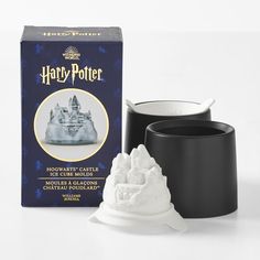 a harry potter hogwarts castle candle holder next to a box of harry potter mugs