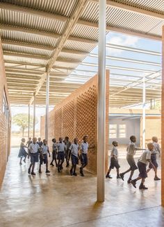 a group of people walking around inside of a building next to tall pillars and wooden slats