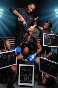 a man standing next to two women with boxing gloves on and signs in front of them